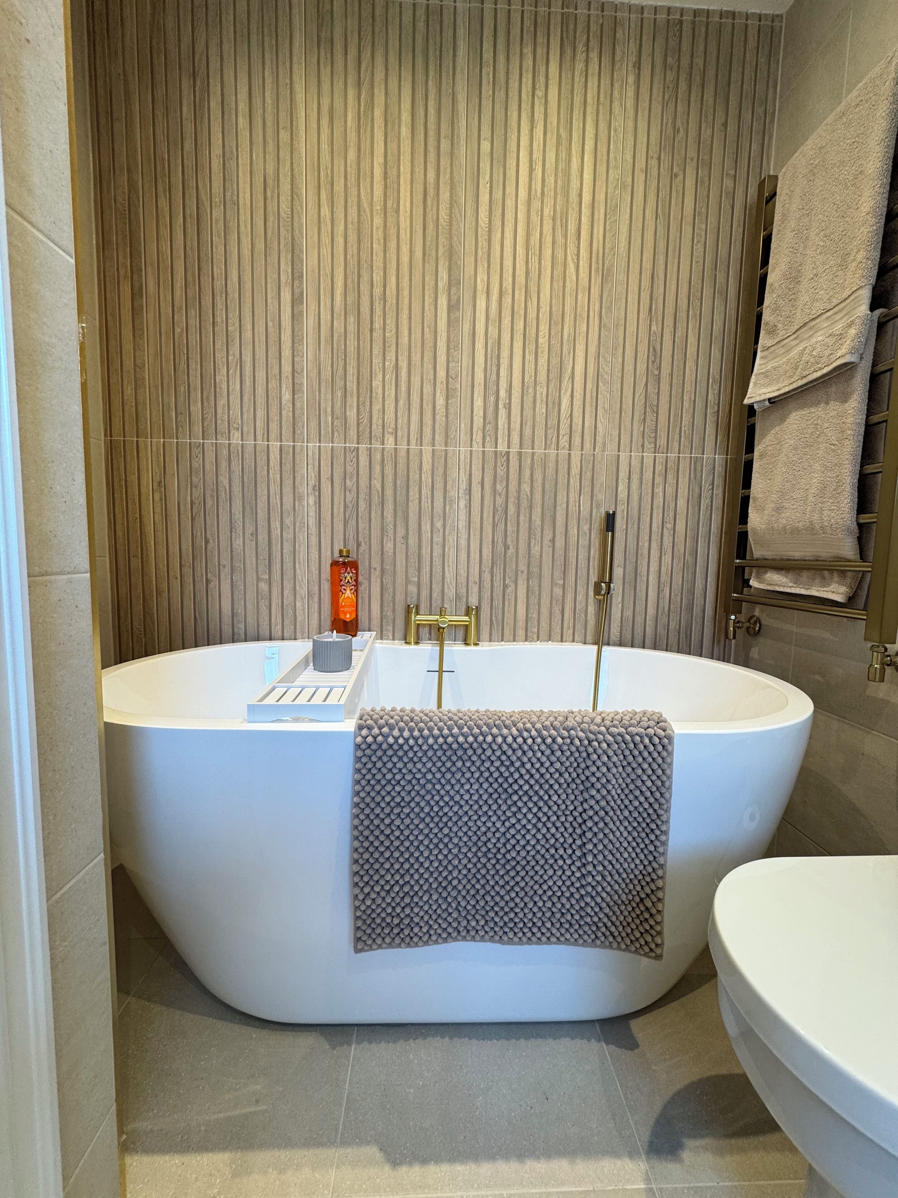 A modern bathroom with a freestanding bathtub, a toilet, and a towel rack.