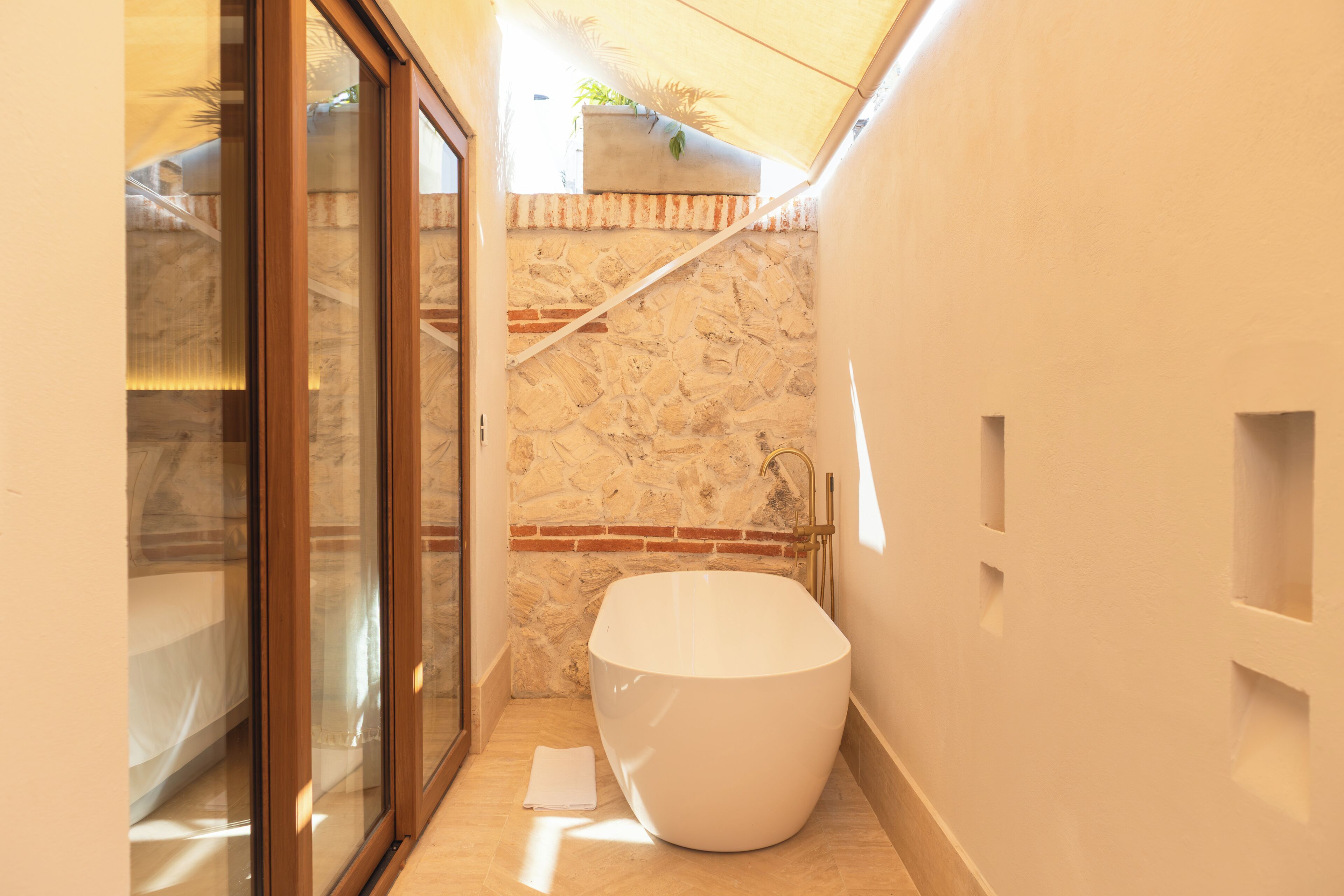 Une salle de bain moderne avec une grande baignoire, une douche en verre et un mur en pierre.