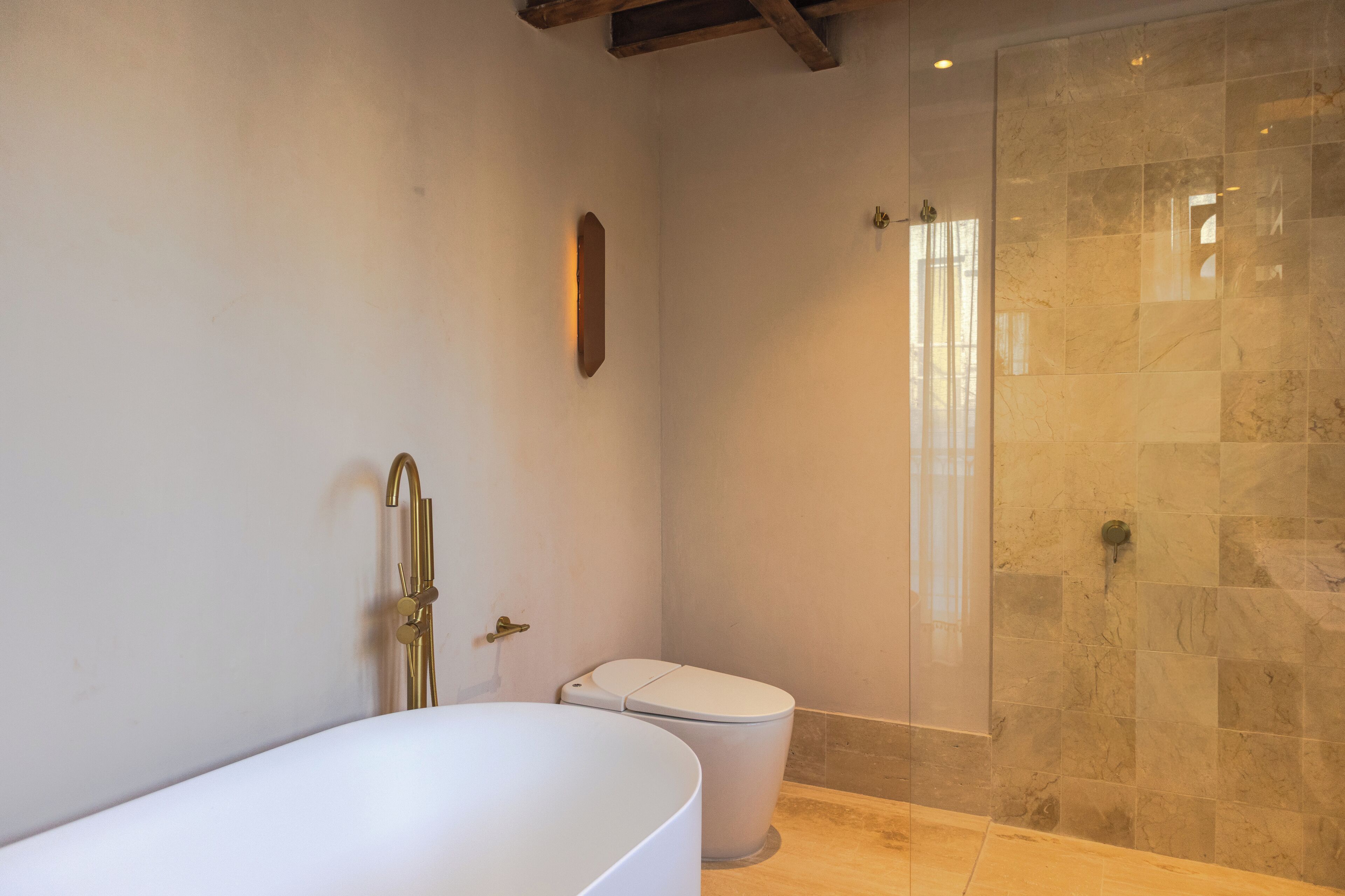 Une salle de bain équipée d’une baignoire, de toilettes et d’une douche séparée par des parois en verre.