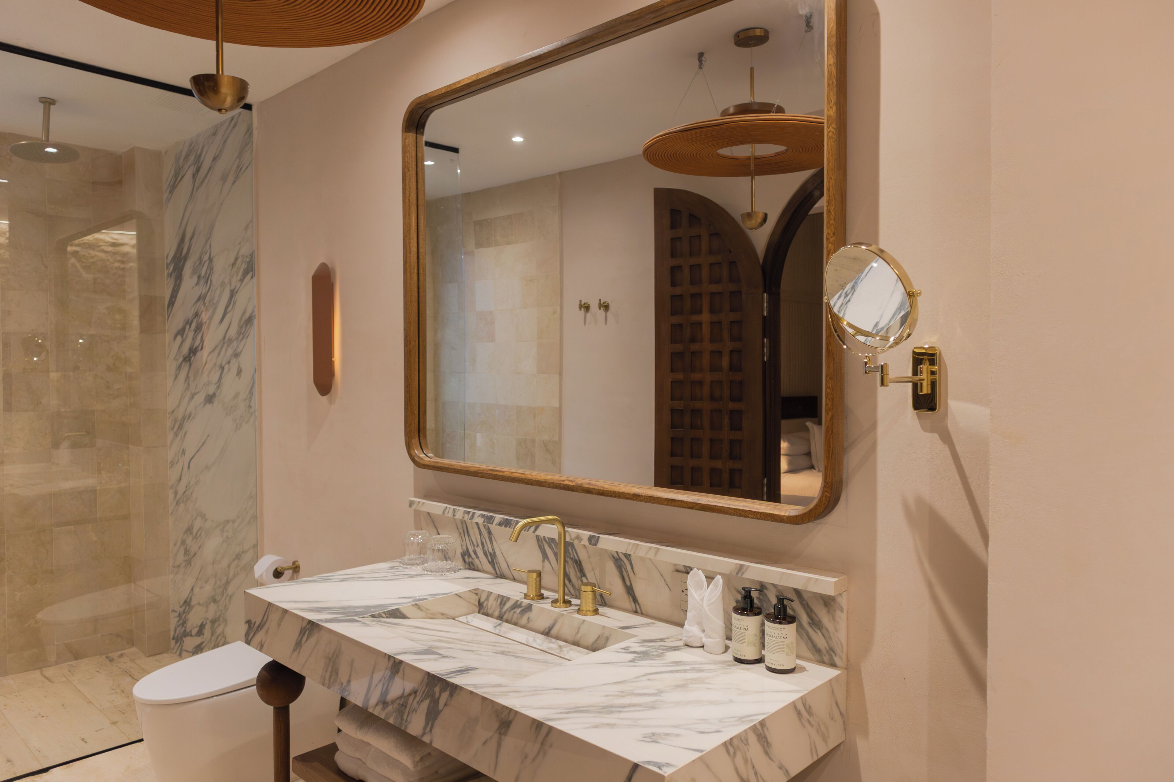 A bathroom with a marble sink, a large mirror, and a shower with a glass door.