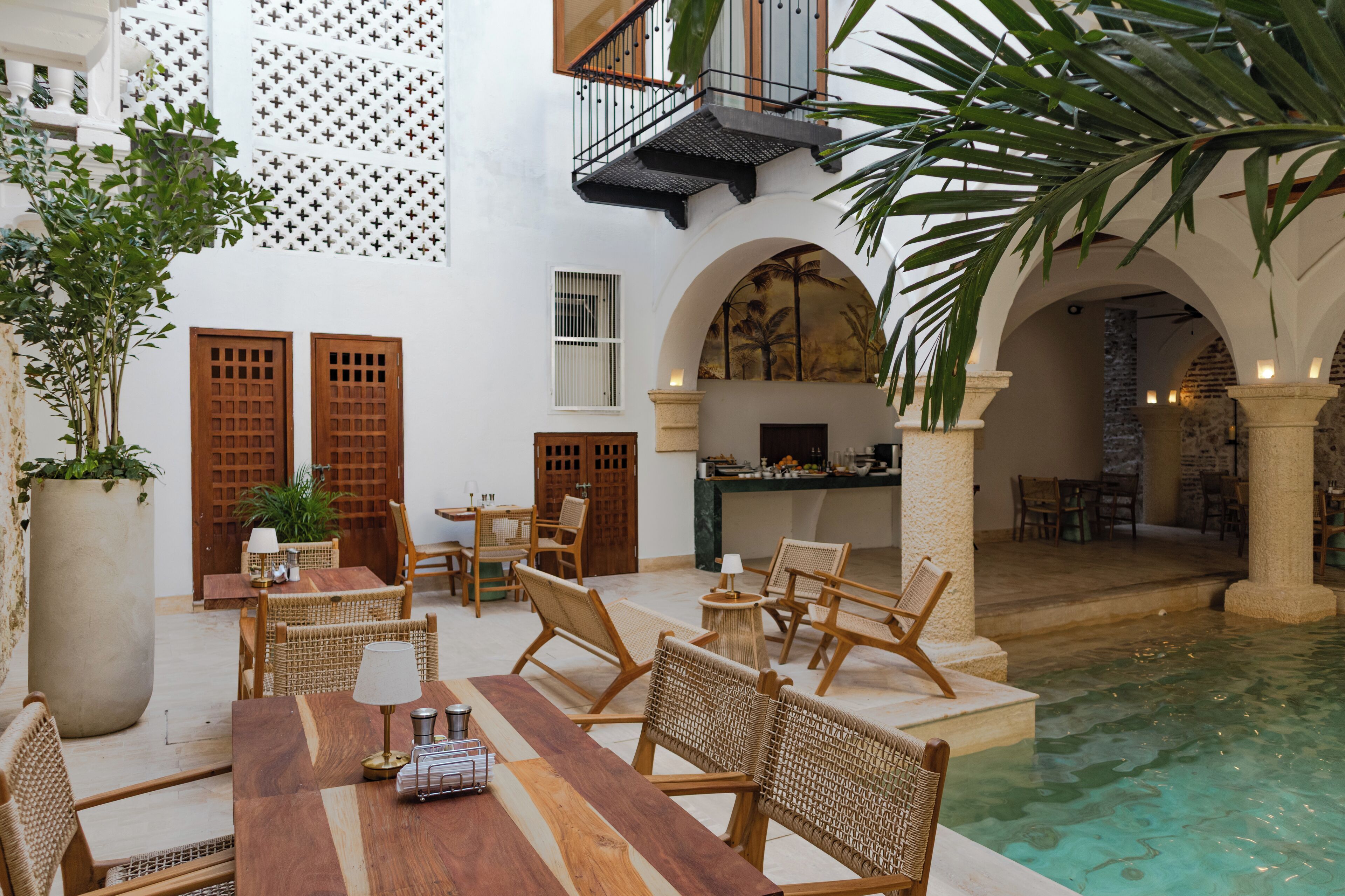 Ein Innenhof mit Pool, Holzmöbeln und einer Essgegend mit Blick auf den Pool.