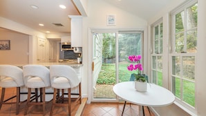 A kitchen with a sliding glass door leading to a garden. There are three bar stools and a round table with a potted plant. - Spacious 5-Bedroom 6 Bed House In Gorgeous Upper Montclair with AC, Theater Room (Upper Montclair)