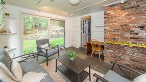 A cozy patio area with a brick wall, a dining table, and a sofa. - Spacious 5-Bedroom 6 Bed House In Gorgeous Upper Montclair with AC, Theater Room (Upper Montclair)