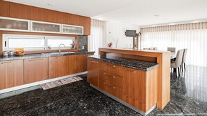 Eine moderne Küche mit Holzausstattung, einer Arbeitsplatte aus Granit und einem Essbereich mit Tisch und Stühlen.