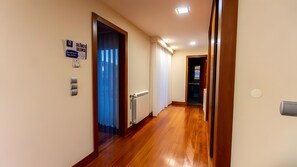 Un couloir avec un plancher en bois, un radiateur, une porte avec une fenêtre et un panneau indiquant qu’il est obligatoire d’observer un silence de 10 minutes.