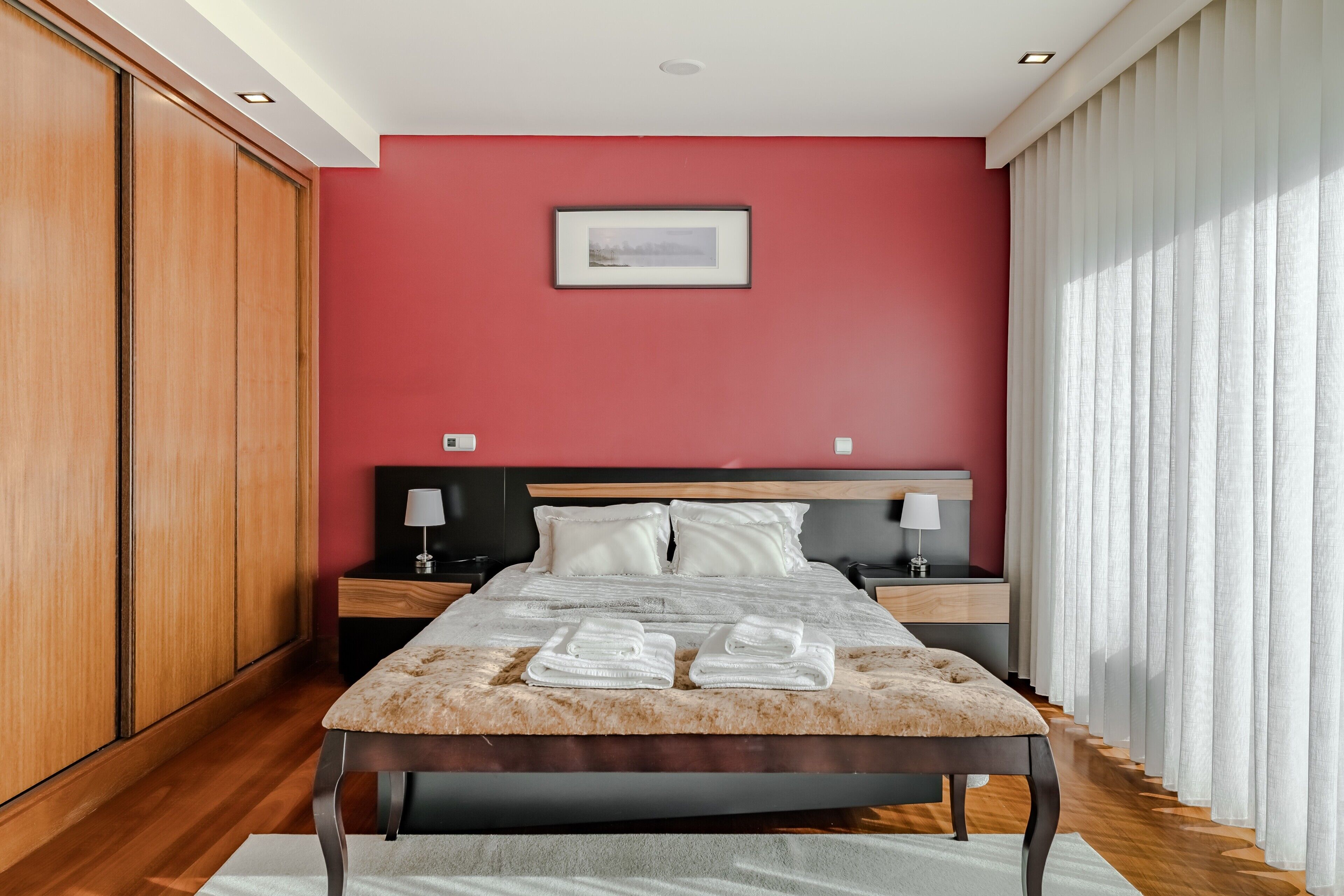 A bedroom with a bed, nightstands, a wooden wardrobe, and a framed picture on the wall.