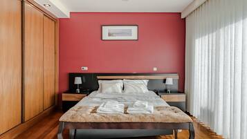 A bedroom with a bed, nightstands, a wooden wardrobe, and a framed picture on the wall.
