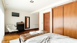 A bedroom with a bed, a chair, a TV, a wardrobe, and a mirror. - Casa Do Chino - Suite with Pool View (Belinho)