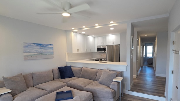 A modern living room with a sectional sofa, a small table, and a ceiling fan. - Talk about Location!!!!    Across from the Beach,Lucy & the GreenHouse (Margate City)