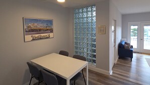 A dining area with a table and chairs, a decorative glass partition, and a framed picture on the wall. - Talk about Location!!!!    Across from the Beach,Lucy & the GreenHouse (Margate City)