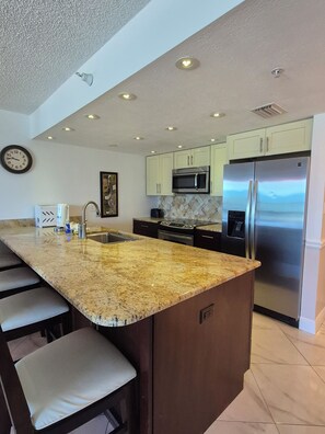 A kitchen with a granite countertop, stainless steel appliances, and a clock on the wall. - NEW UPGRADES on lovely Indian Rocks Beach (Indian Rocks Beach)