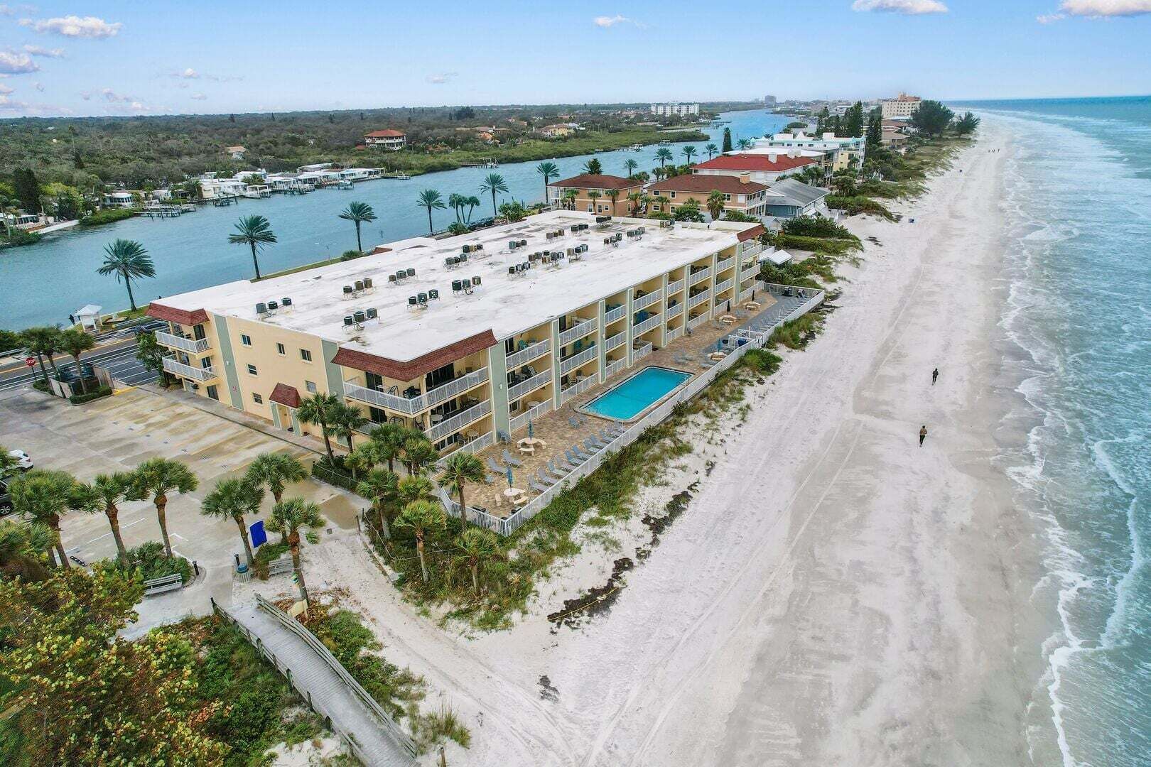 Ein Hotel direkt am Strand mit Pool, mehreren Balkonen und Meerblick.