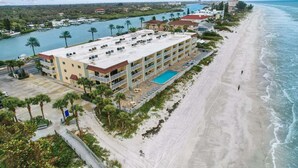 A beachfront hotel with a pool, multiple balconies, and a view of the ocean.