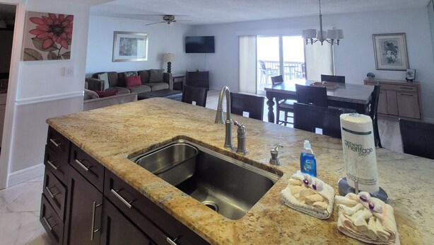 A modern kitchen with granite countertops, stainless steel sink, and a dining area with a table and chairs.