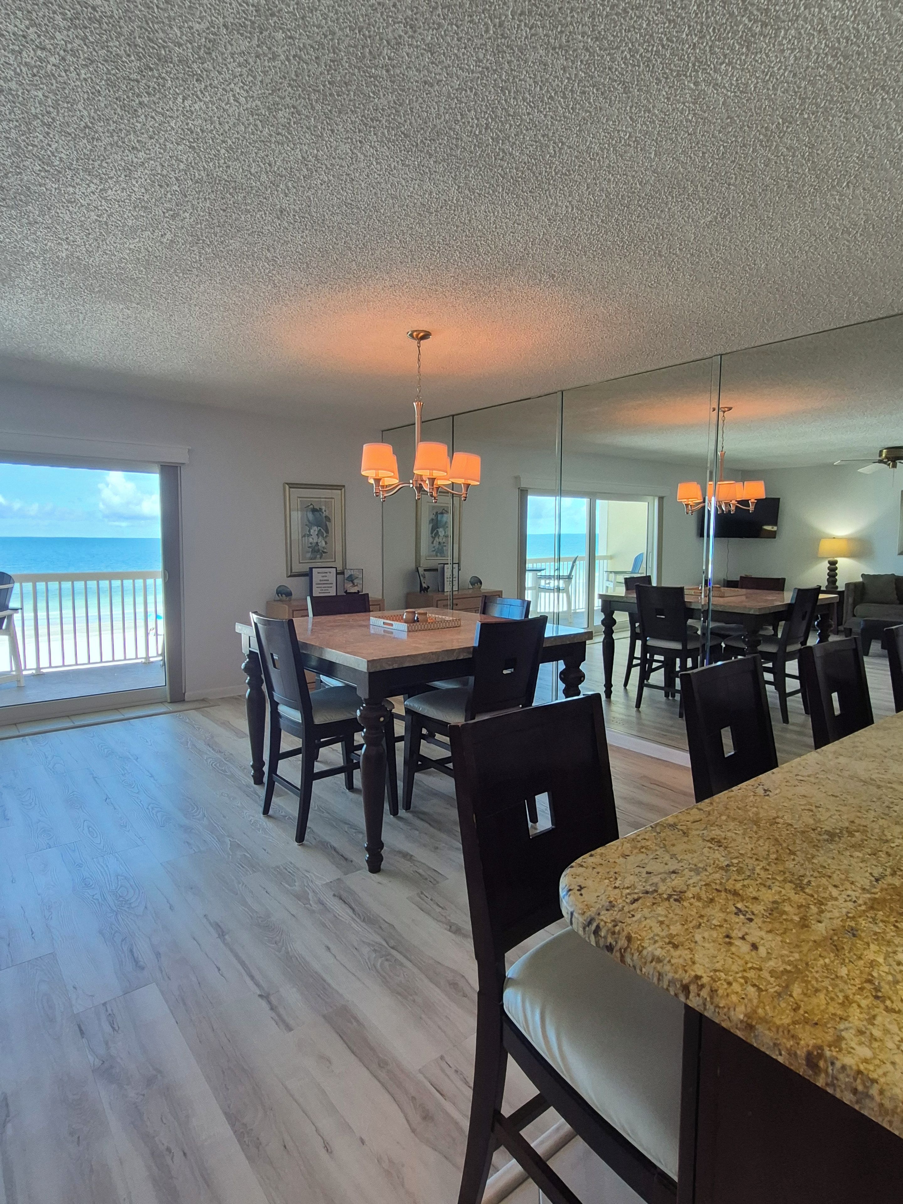 A spacious dining area with a view of the ocean, a large dining table, and multiple chairs.