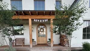 Een modern huis met een houten veranda, een middendeur met een krans, en een verzorgde tuin met stenen paden.