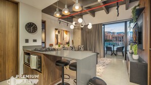Een moderne keuken met een centraal eiland, barkrukken, een inbouwoven en een groot raam met uitzicht op de stad.