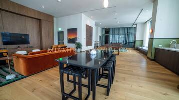 Een moderne hotel lobby met een lange eettafel, comfortabele zithoek, een flatscreen televisie en een groot raam met uitzicht.
