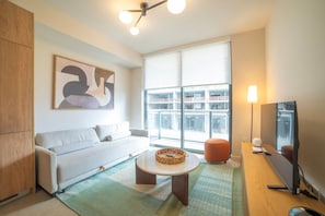 Un salon moderne avec un canapé, une table basse, un téléviseur et une grande fenêtre.