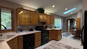 Una cocina moderna con armarios de madera, un lavavajillas negro y un tragaluz.