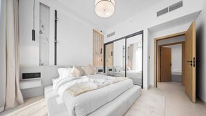 Een moderne slaapkamer met een groot bed, nachtkastje, kledingkast en spiegel.