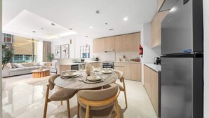Eine moderne Küche mit einem Edelstahl-Kühlschrank, Holzschränken und einem Essbereich mit rundem Tisch und Stühlen.