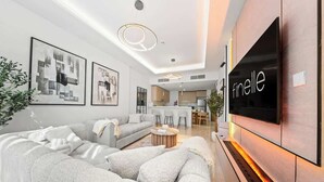 Ein modernes Wohnzimmer mit einem großen Flachbildfernseher, einer Couch und einem Couchtisch.