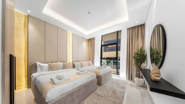 Ein modernes Hotelzimmer mit einem großen Bett, einer Schlafcouch, einem Flachbildfernseher und einem großen Fenster mit Vorhängen.