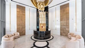 A modern lobby with a central column, seating areas, and a patterned wall. - JVC 1BR nr Circle Mall | Sleeps 7 | Pool & Gym (Dubai)