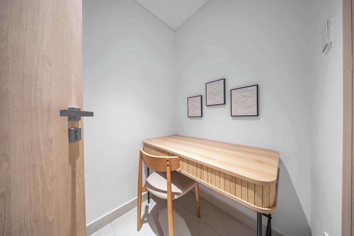 A corner room with a wooden desk, a chair, and three framed artworks on the wall.