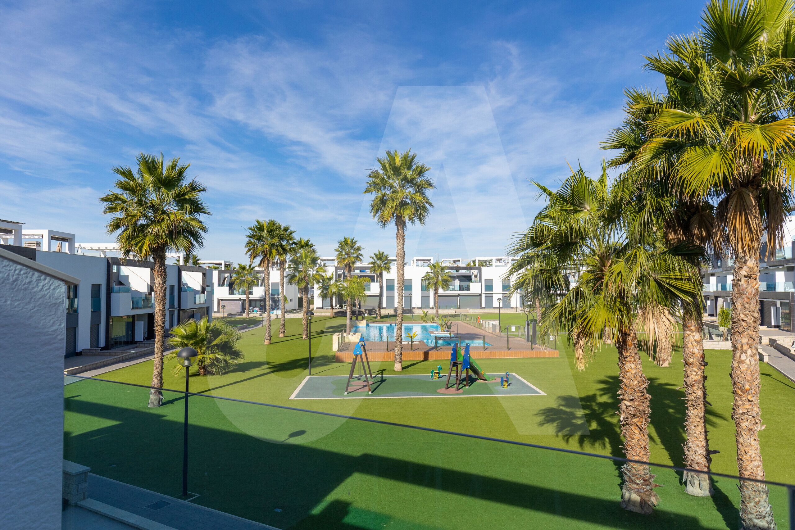 Ein Innenhof mit Palmen, einem Basketballplatz und modernen Gebäuden.