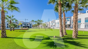 A golf course with palm trees and modern buildings in the background. - Casa Marina in Guardamar (Guardamar del Segura)