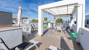 A rooftop terrace with outdoor seating, a pergola, and a pool in the background. - Casa Marina in Guardamar (Guardamar del Segura)
