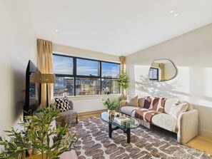 A modern living room with a sofa, armchair, and a glass coffee table. - Modern St Pancras Apartment (Greater London)