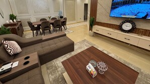 Ett modernt vardagsrum med en hörnsoffa, en matplats och en TV som är monterad på väggen.