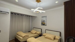 Quarto moderno com duas camas, luminária no teto e aparelho de ar condicionado.