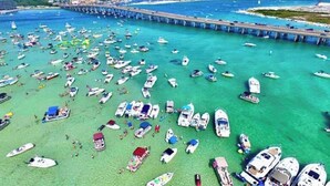 Un port de plaisance où de nombreux bateaux sont amarrés et où se trouvent des personnes sur la rive.