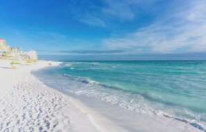 A beach with white sand, clear turquoise water, and a few buildings in the background. - Rose of Destin - Sleeps 12 - Mediterranean styling on 4-Prong Lake, Destin (Destin)