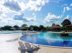 Un área de piscina con sillones de descanso, un tobogán y un pabellón.