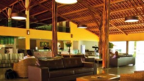 A lobby with a high ceiling, a reception desk, seating area with sofas, and a large vase. - Hotel Canariu's Gravatá (Gravatá)