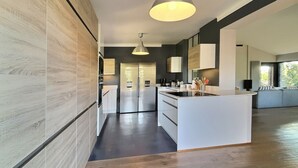 Una cocina moderna con una isla central, electrodomésticos de acero inoxidable e iluminación colgante.