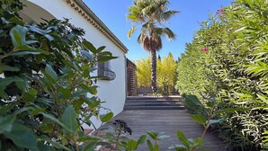 Un camino que lleva a un edificio con fachada blanca y una palmera al fondo.