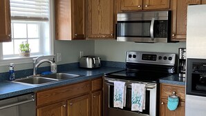 Uma cozinha moderna com armários de madeira, eletrodomésticos de aço inoxidável, micro-ondas embutido e máquina de lavar louça.
