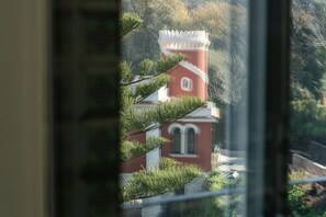 A red building with a white tower, surrounded by greenery. - Signature Villa Overlooking the Gulf of Naples with biolake and garden (Vico Equense)