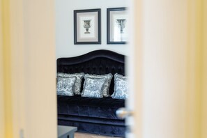 A dark-colored sofa with patterned cushions in a room with framed artwork on the wall. - Signature Villa Overlooking the Gulf of Naples with biolake and garden (Vico Equense)