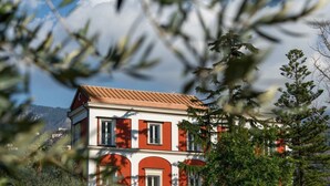 Ein zweistöckiges Gebäude mit roter und weißer Fassade, zahlreichen Fenstern und einem geneigten Dach.