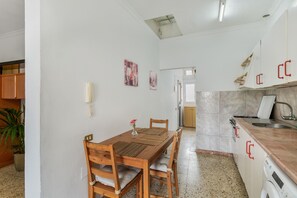 A kitchen with wooden cabinets, a countertop, a sink, and a washing machine.