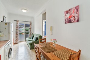 En kompakt opholdsstue med spisebord, stole, sofa, vaskemaskine og køleskab.