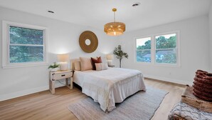 A bedroom with a large bed, bedside tables, a hanging light fixture, and two windows. - Casa Azul an interior designed home in Stonehaven.Security System,Fiber Internet (Charlotte)