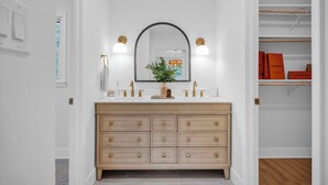 A modern bathroom with a vanity, a mirror, and a walk-in closet. - Casa Azul an interior designed home in Stonehaven.Security System,Fiber Internet (Charlotte)